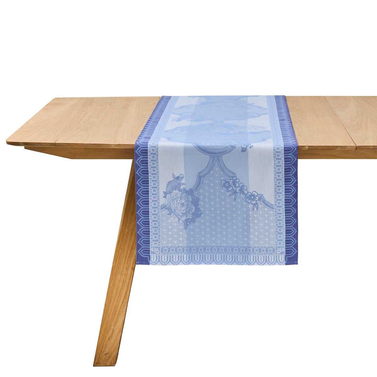 Blue floral table runner on a wooden table with a white background