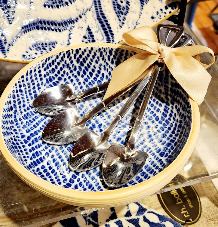 Set of silver spoons in a blue and white patterned bowl with a beige ribbon.
