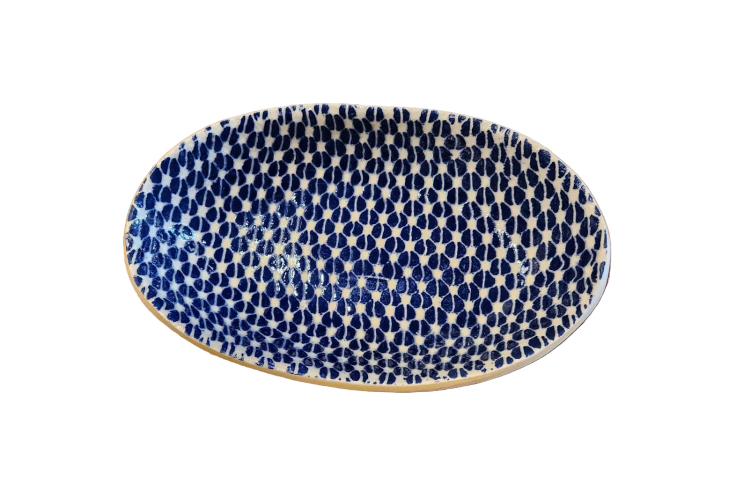 An oval ceramic serving platter with a blue and white fish-scale pattern, displayed on a rustic wooden surface.