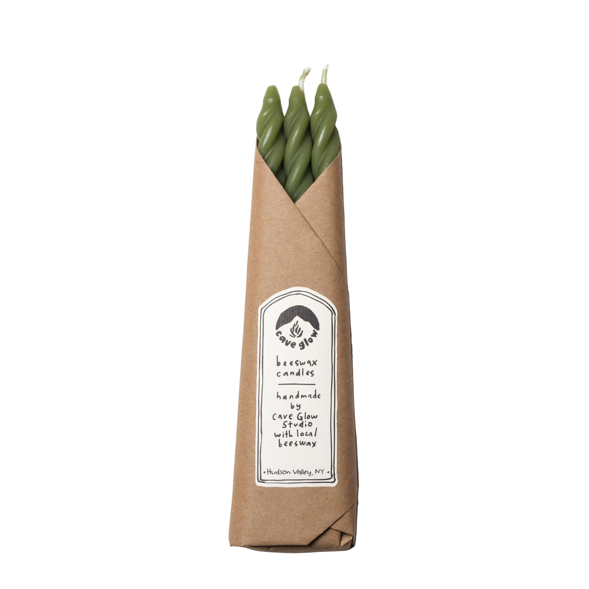 Three green candles in a brown paper sleeve with a label on a white background