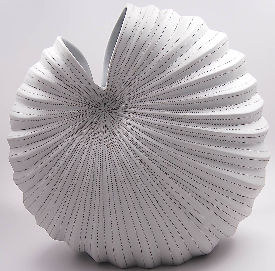 White decorative pillow with a textured, fan-like design on a light gray background
