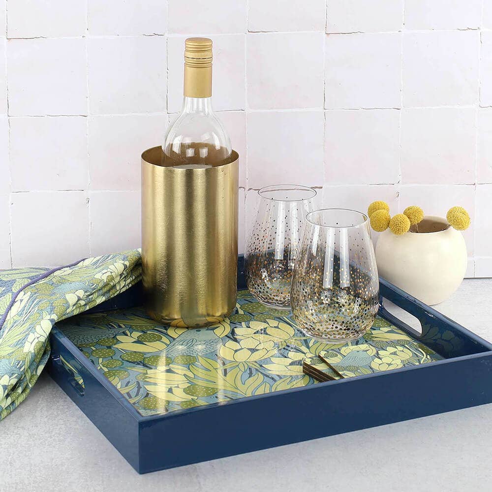Decorative tray with a bottle, glasses, and decorative items on a tiled surface.