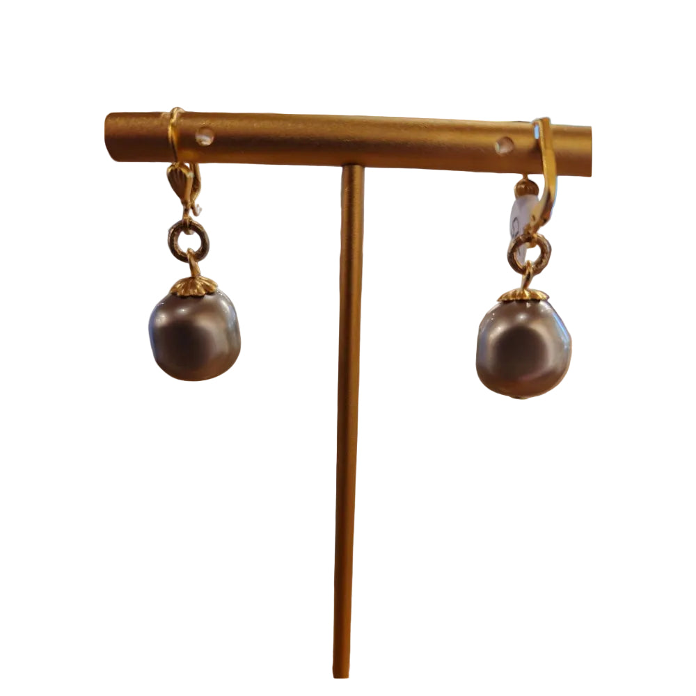 Pair of pearl earrings with gold clasps on a wooden surface