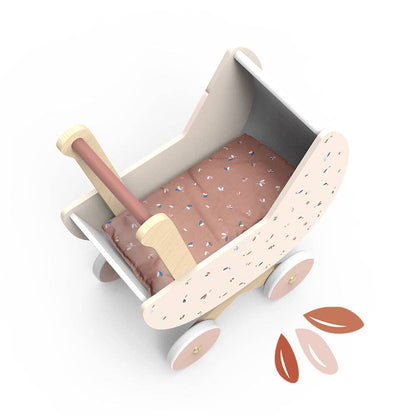 Wooden toy bed with pink bedding on a white background