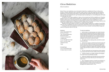 Madeleines on a tray with a cup of tea and a recipe for Citrus Madeleines on a marble surface.