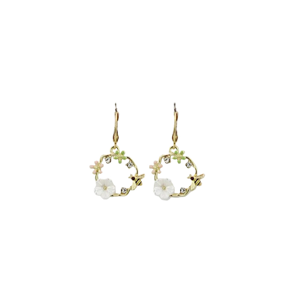 Pair of gold earrings with floral designs on a light gray background