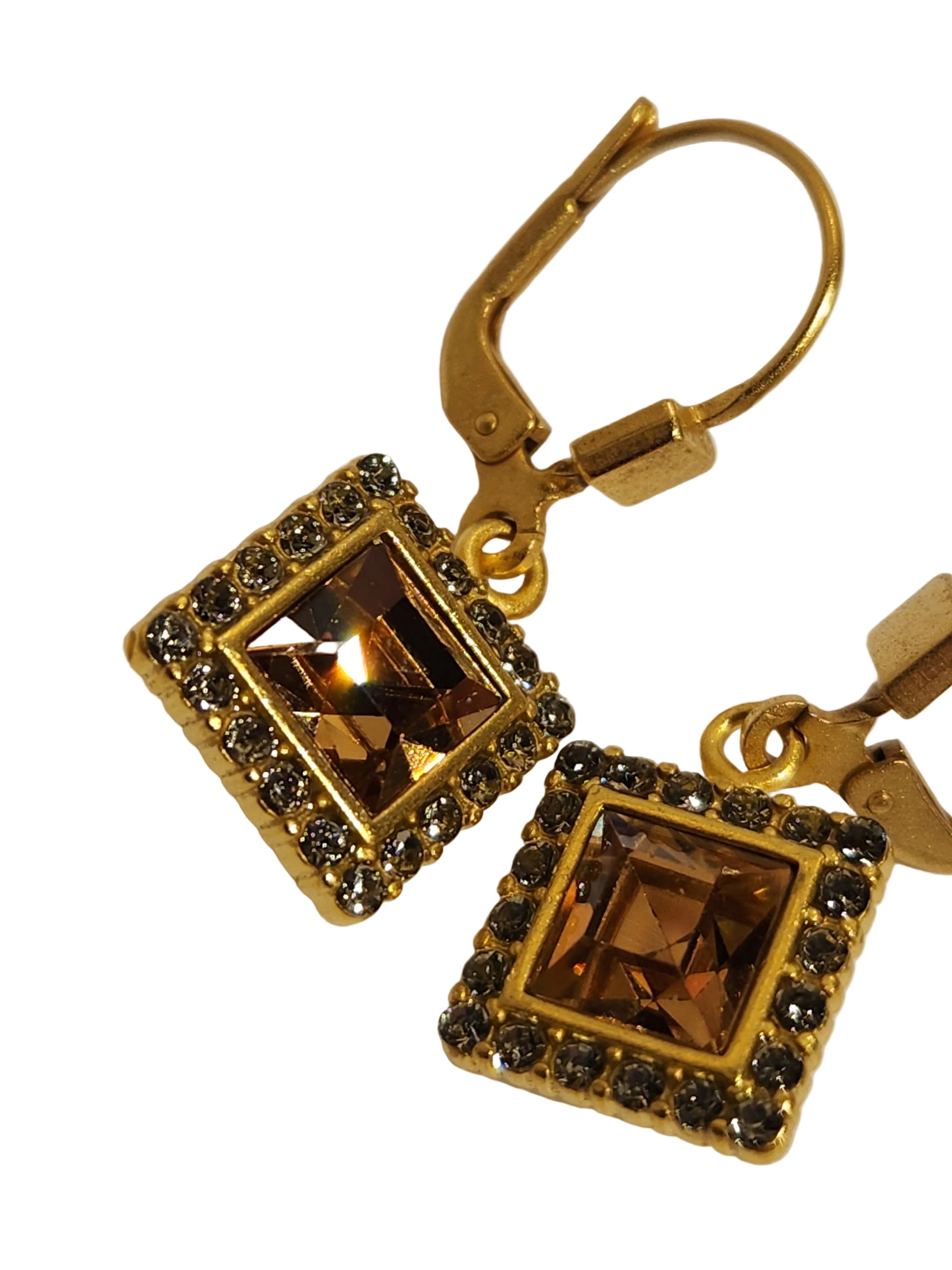 Gold earrings with square gemstones on a light background