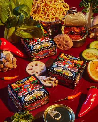 Assorted food items including noodles, vegetables, and spice boxes on a red surface.
