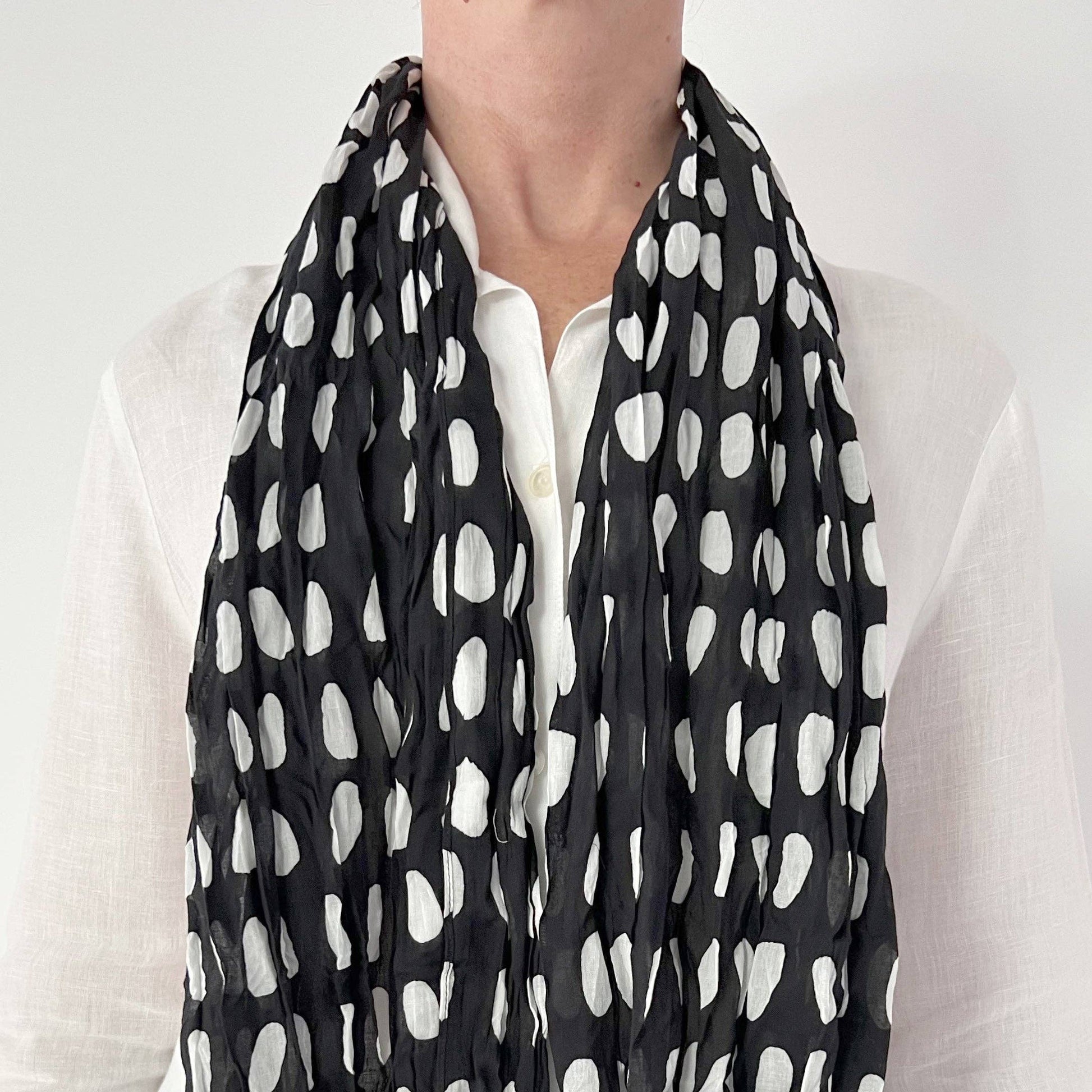 Person wearing a black and white polka dot scarf
