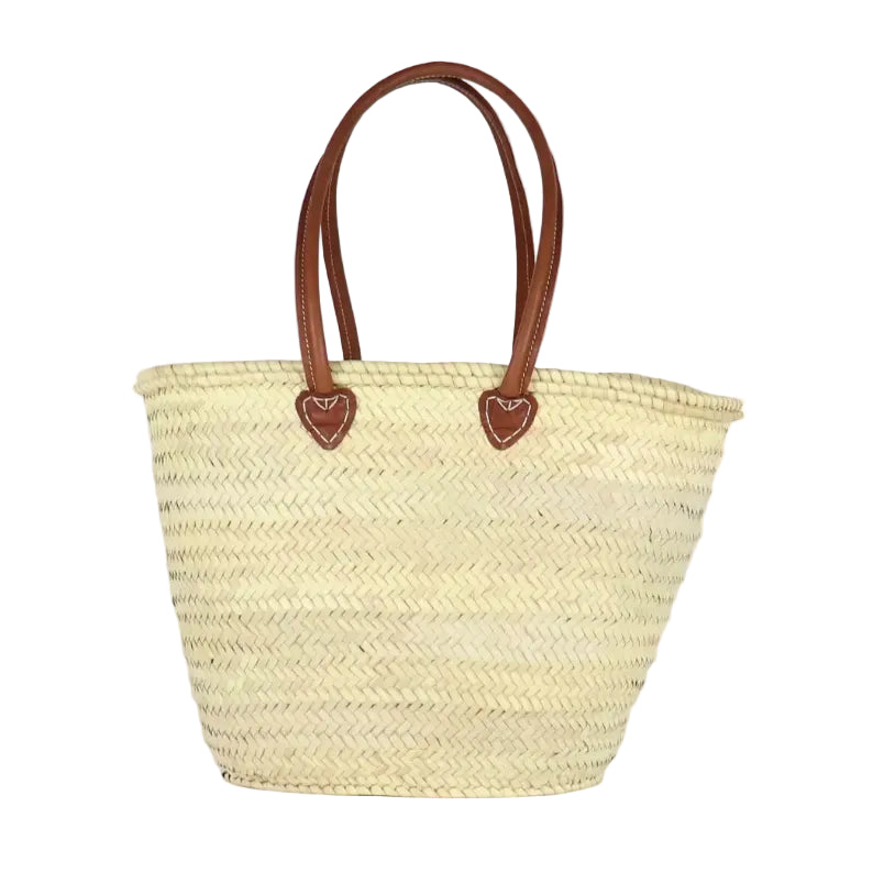 Woven straw tote bag with brown leather handles on a white background