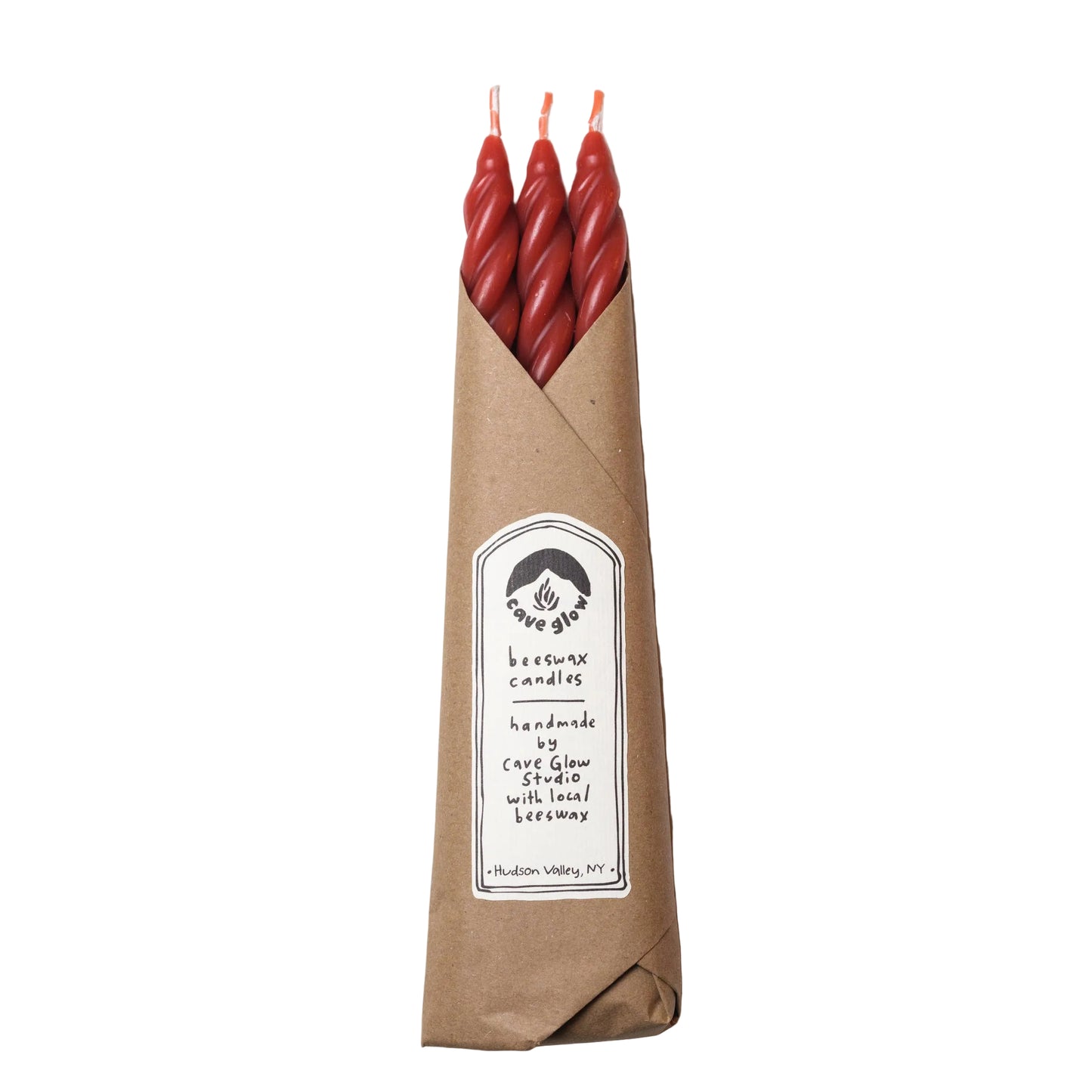Three red twisted candles in a brown paper bag with a label on a white background