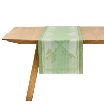 Green patterned table runner on a wooden table with a white background