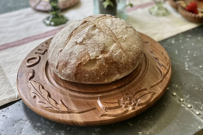 Loaf of bread on a wooden board with decorative edges