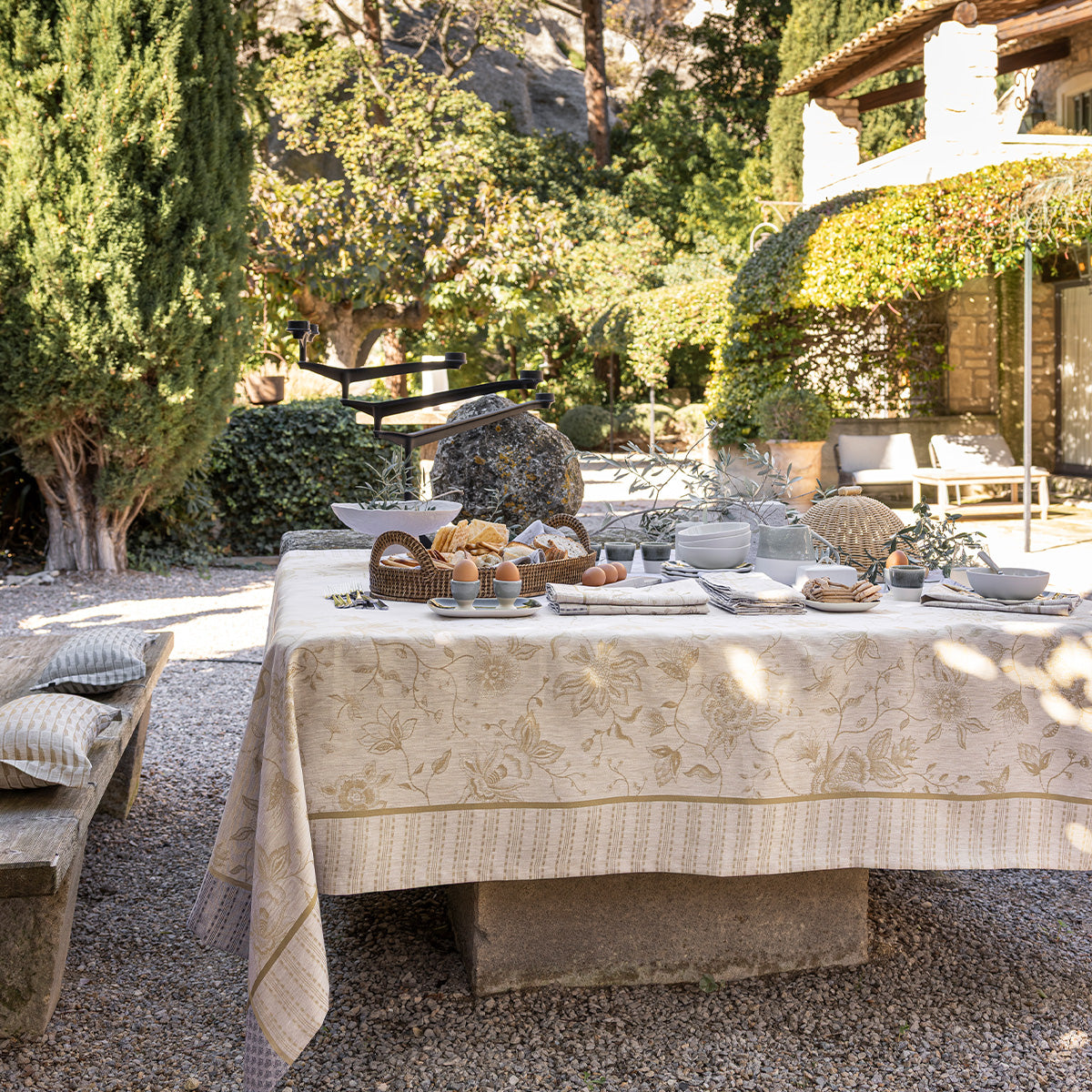 Outdoor dining setup with a tablecloth, plates, and bread in a garden setting.