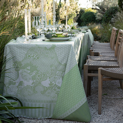 Outdoor dining setup with a patterned green tablecloth and chairs in a garden setting.