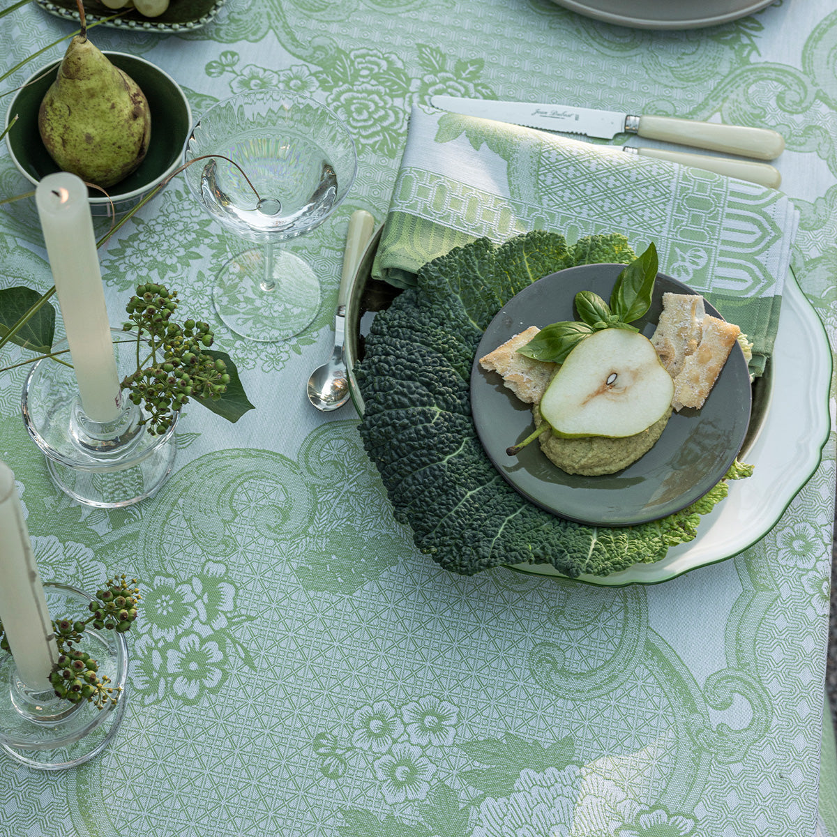 Table setting with green tablecloth, plate of food, and decorative elements.