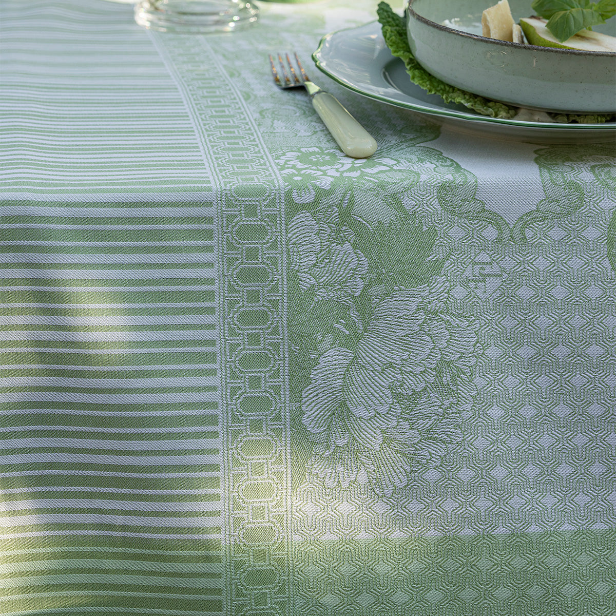 Green and white patterned tablecloth with a plate and fork on a table.