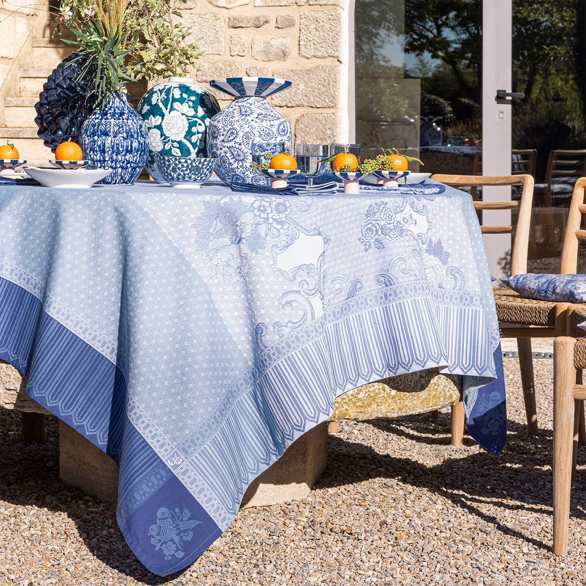 Outdoor table setting with blue and white tablecloth and decorative items.
