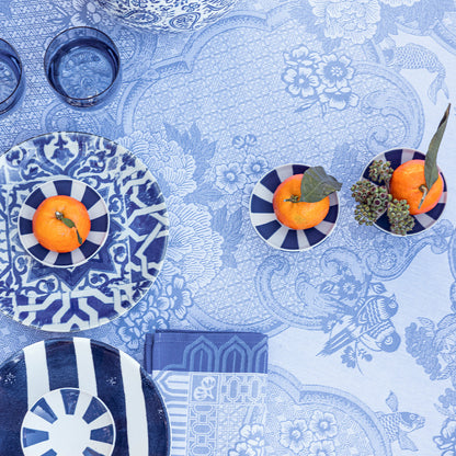 Decorative table setting with blue and white plates, pumpkins, and a patterned coated tablecloth.