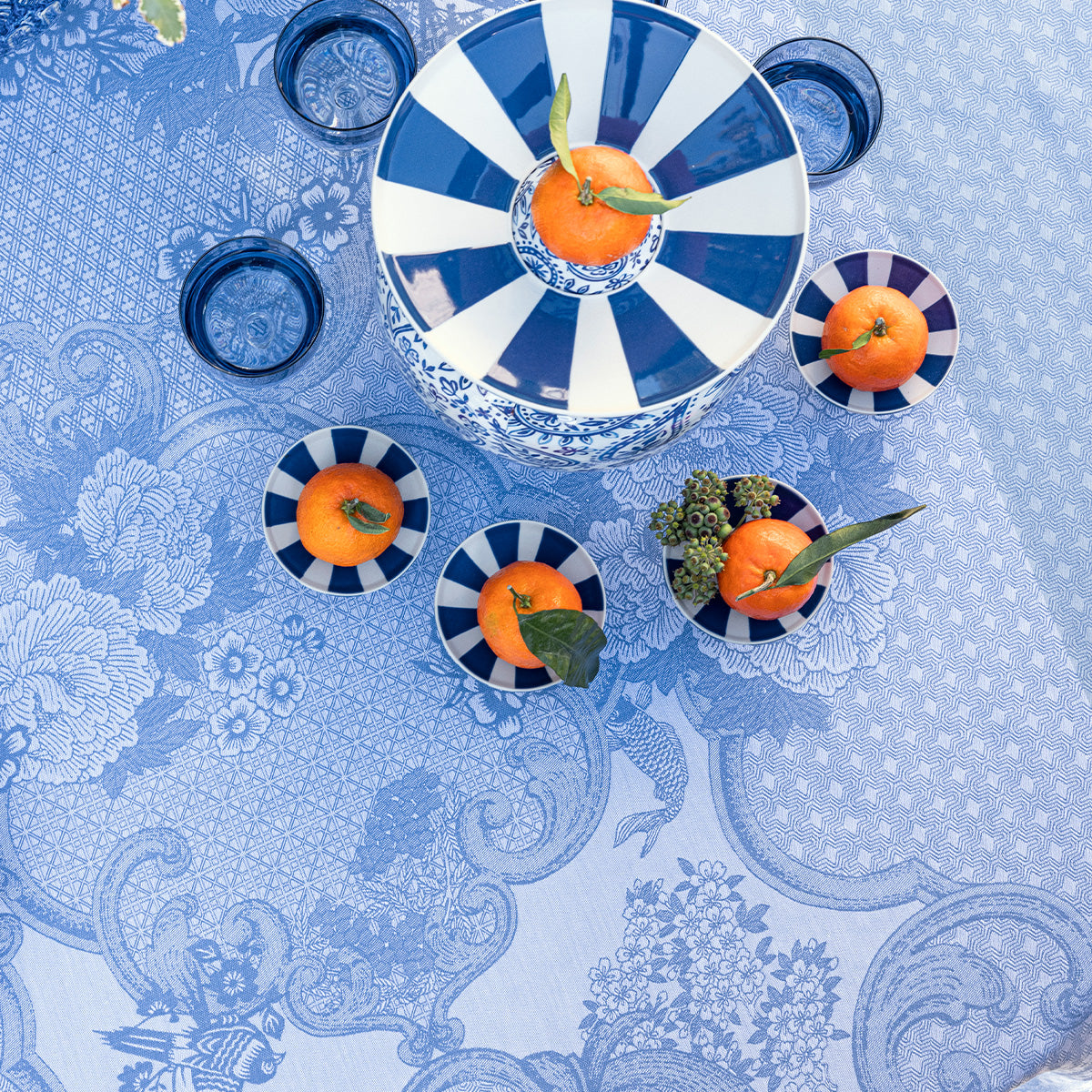 Blue and white patterned tablecloth with decorative plates and oranges.
