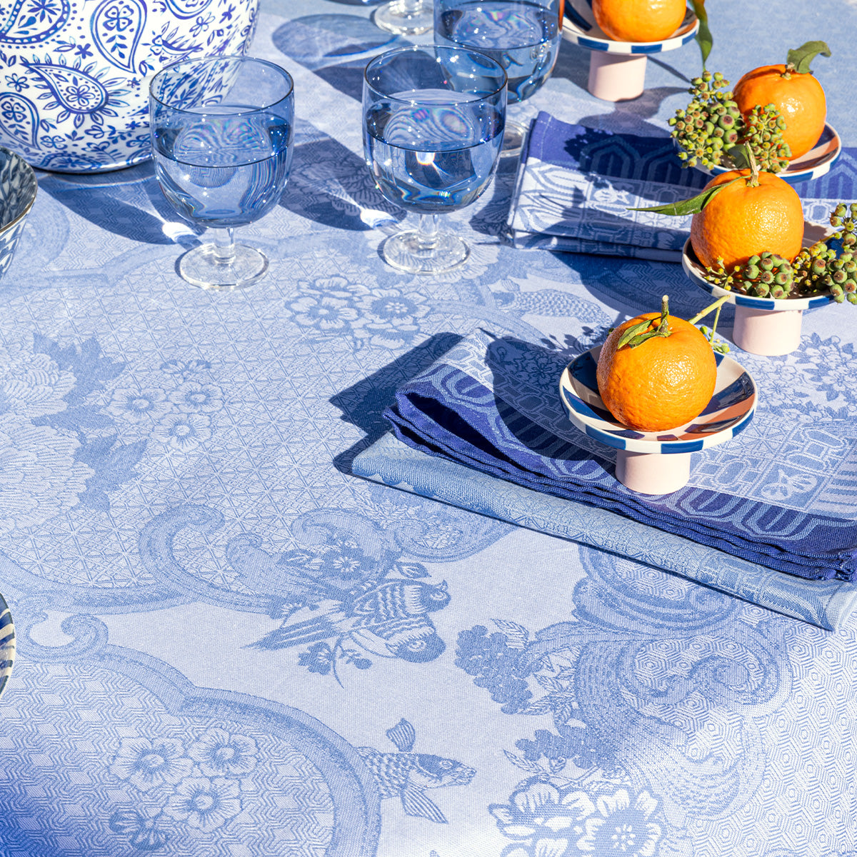Table setting with blue and white patterned tablecloth, glasses, and decorative elements.