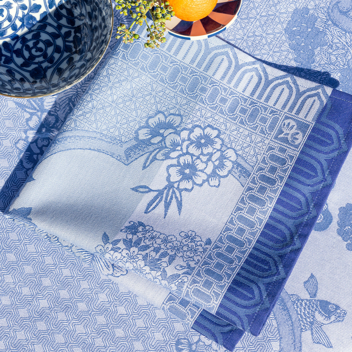 Blue patterned tablecloth with floral designs on a table setting.