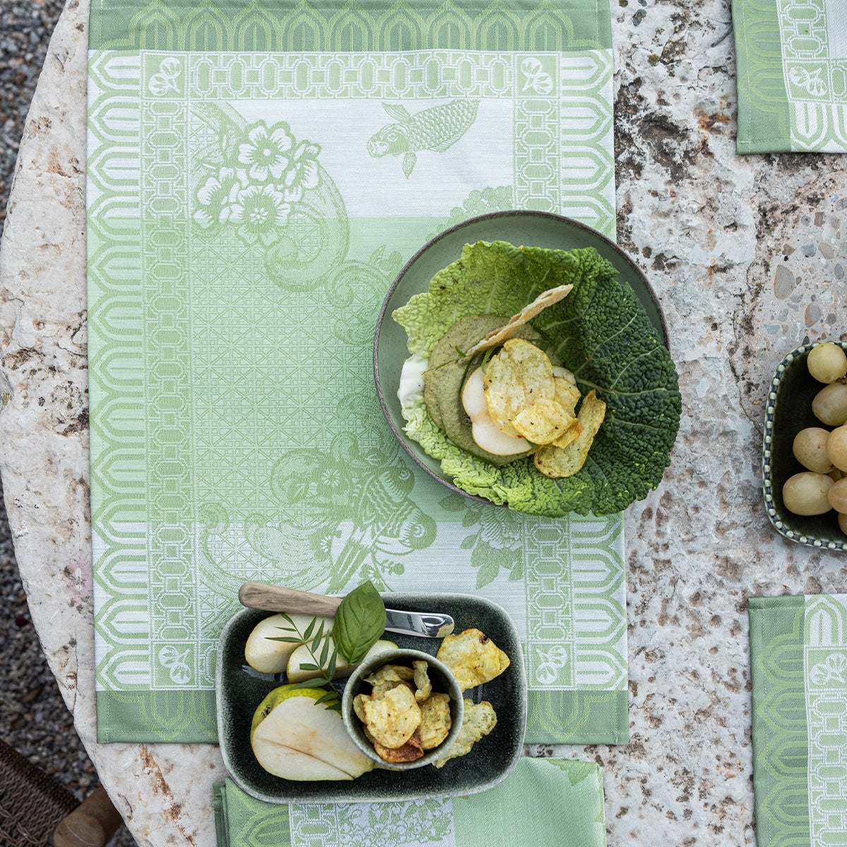 Green patterned placemats with food on a stone surface