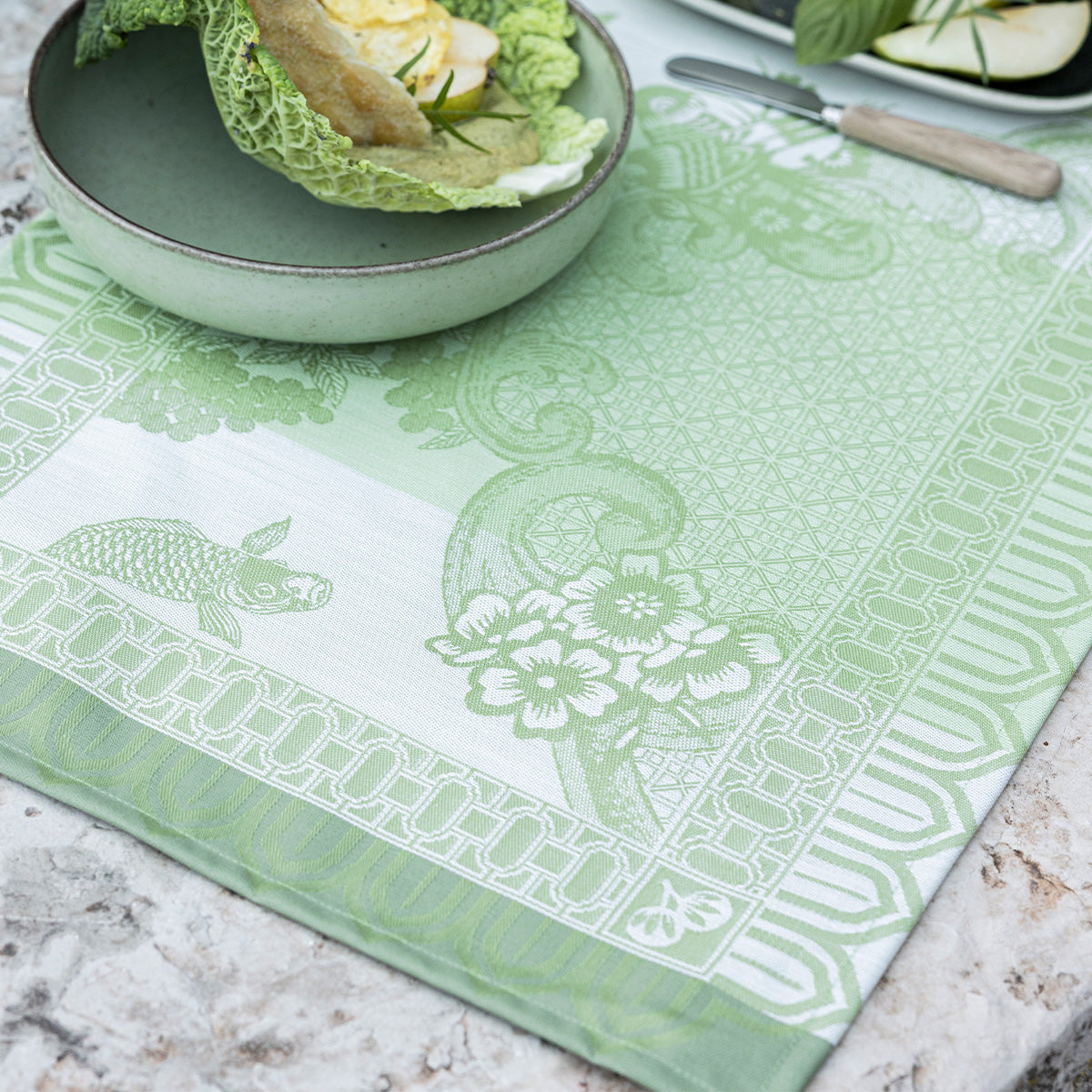 Green patterned tablecloth with turtle design on a marble surface