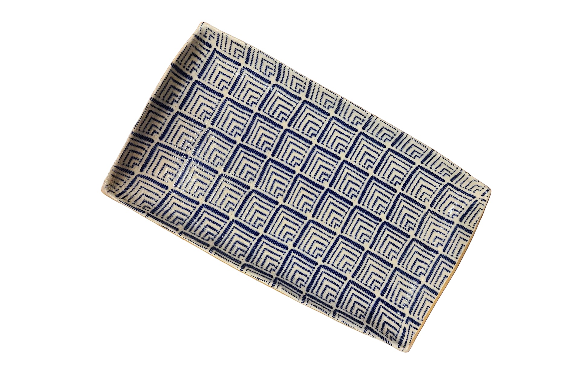 A rectangular woven tray with a geometric Greek key pattern in navy blue and cream, shown on a rustic wooden plank floor.