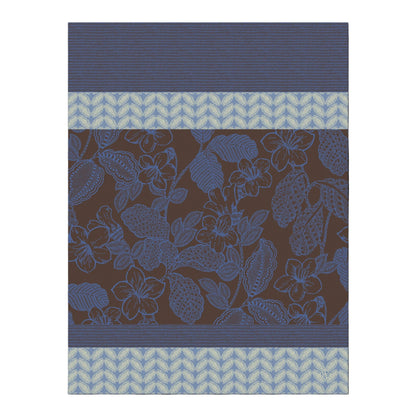 A close-up of a fabric or wallpaper pattern featuring a dark brown background with a blue floral vine design, bordered by blue striped and light blue chevron bands.
